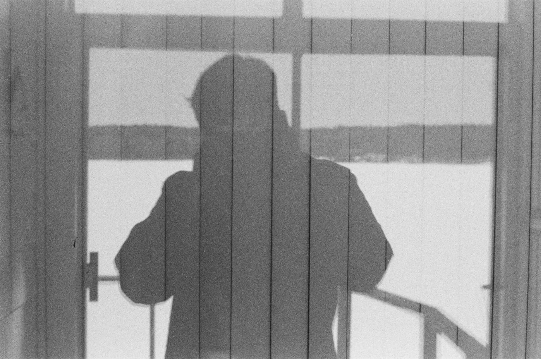 Person looking out a window silhouette in black and white.