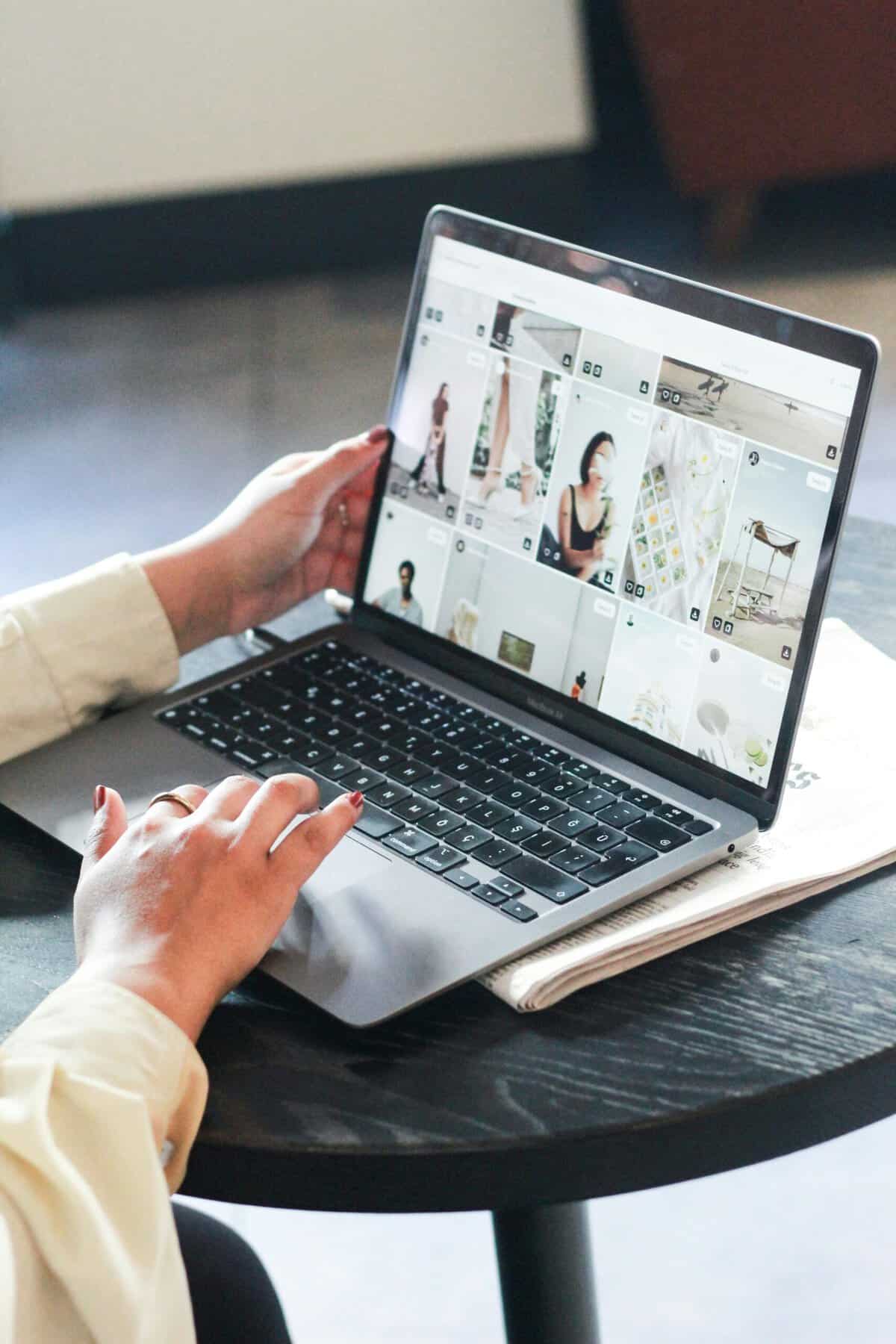 Person working on a laptop with digital images and design projects open on screen.